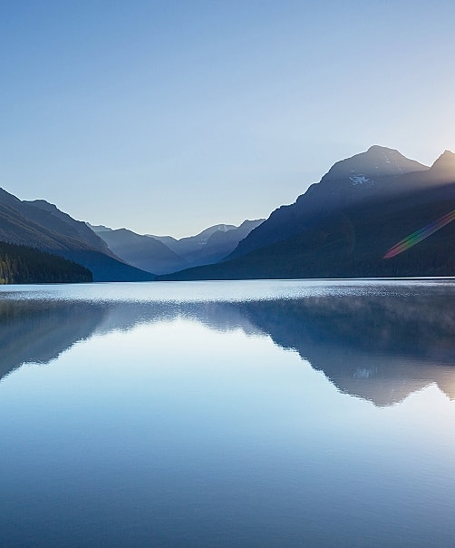 Mountain reflection on calm lake at sunrise.