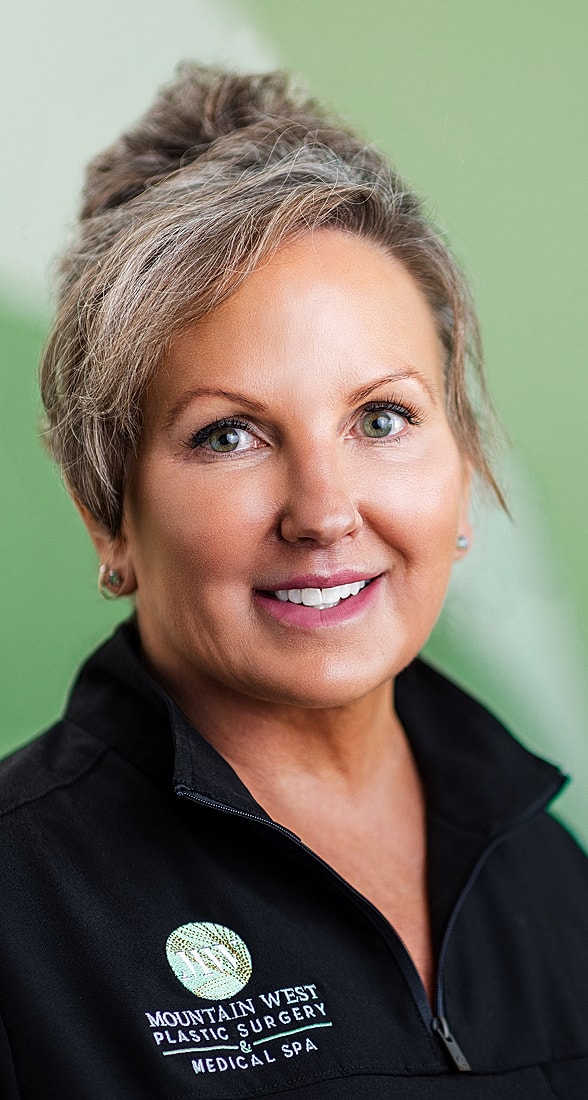 Smiling woman in medical attire, green background.