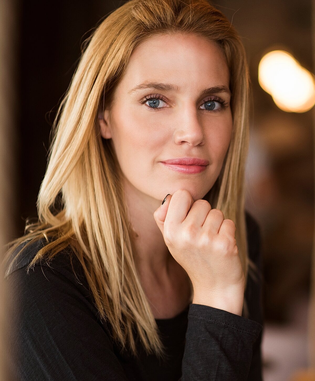 Woman with blonde hair resting chin on hand
