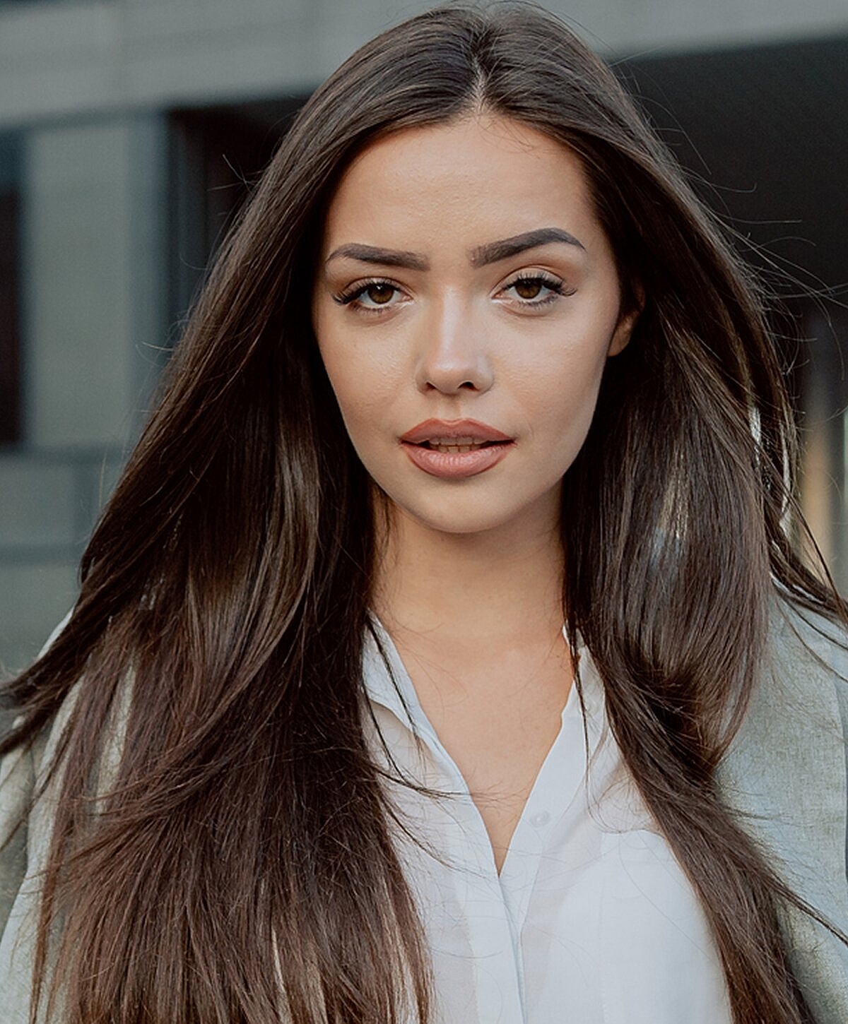 Woman with long hair, neutral expression outdoors.