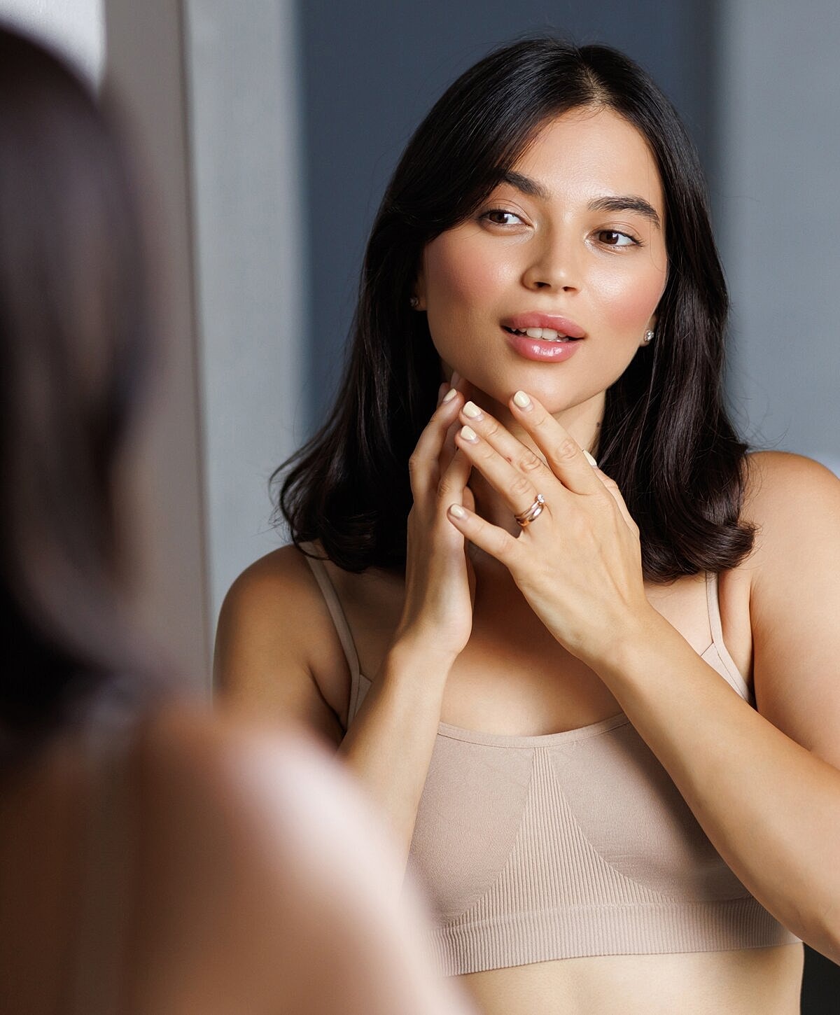 Woman applying skincare in front of mirror.