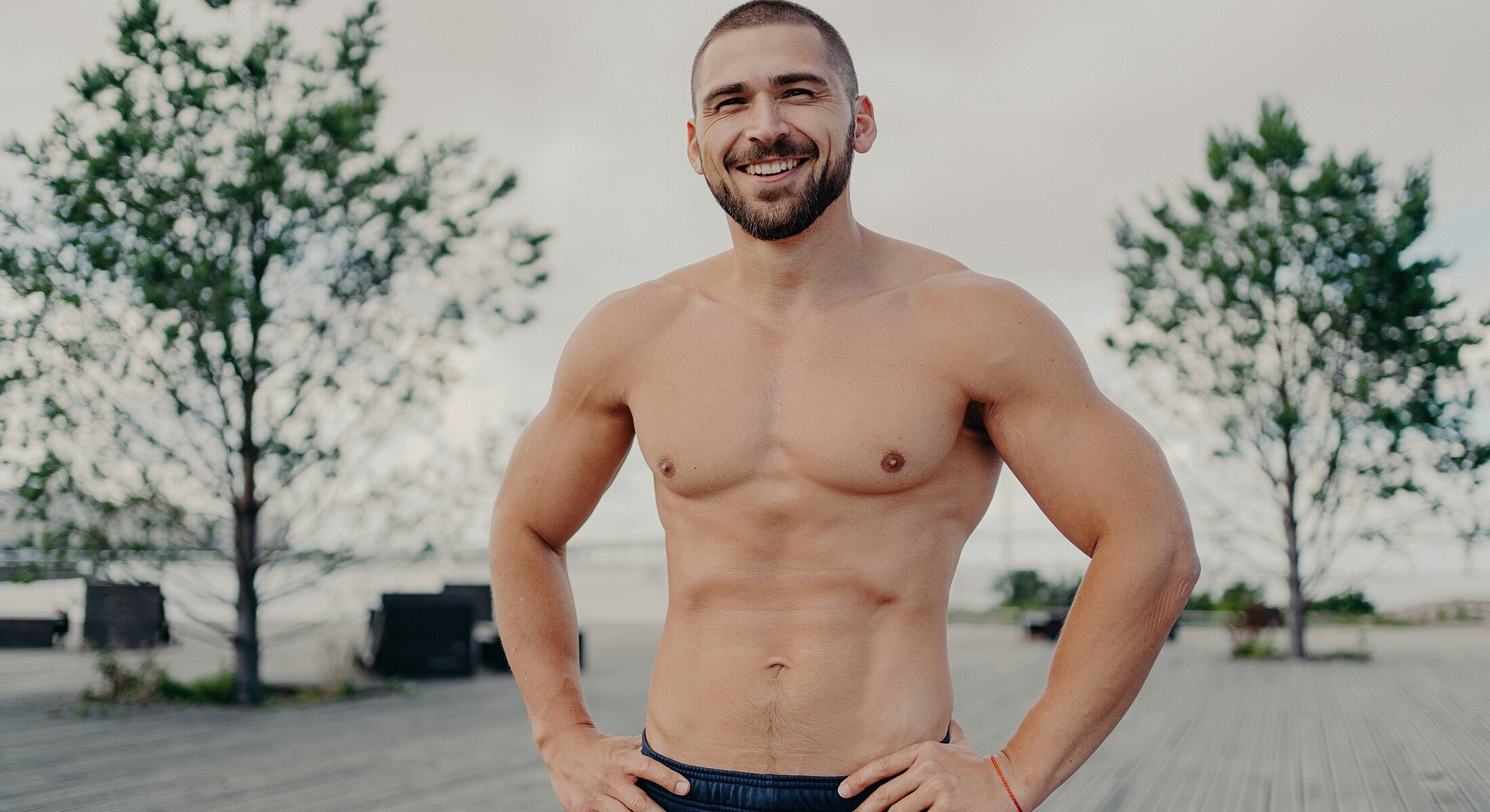 Smiling man with a toned physique outdoors.