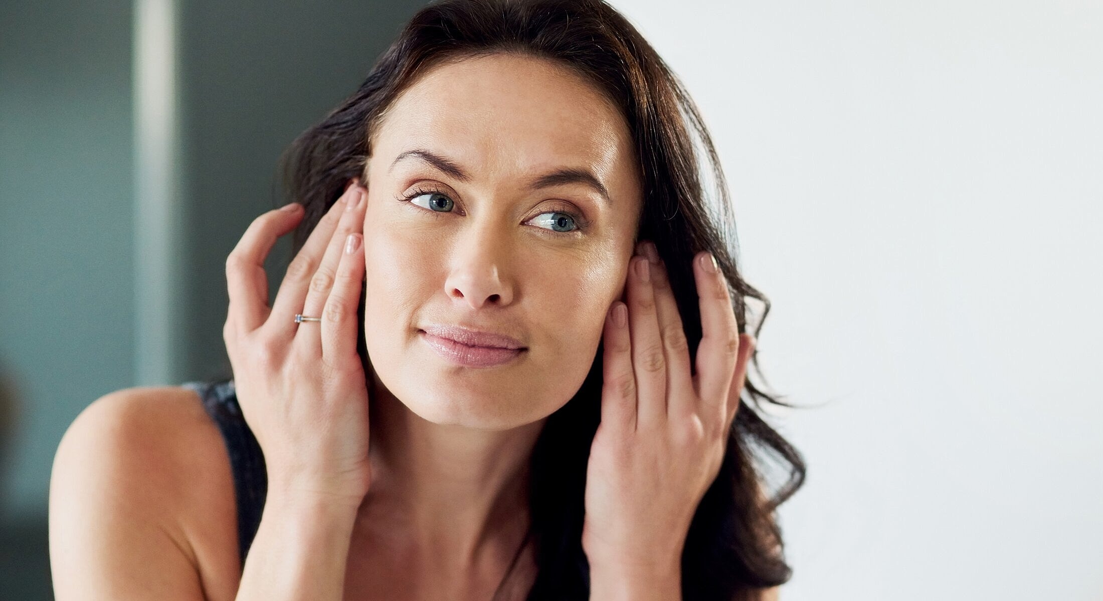 Woman gently touching her face and smiling.